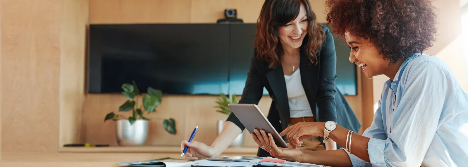 Two professionals collaborating in a modern office with a tablet and paperwork.