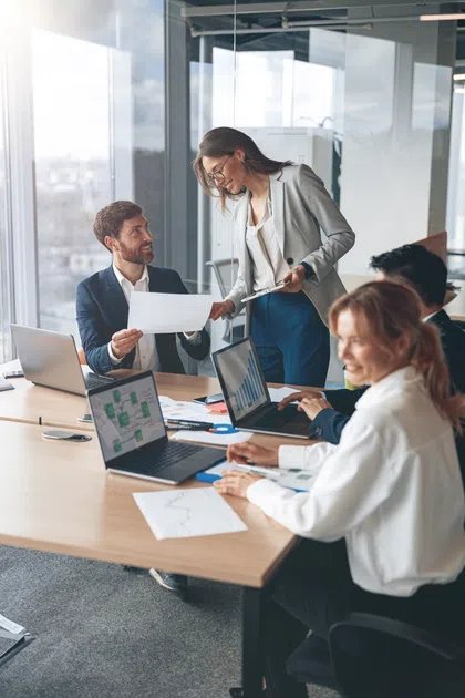 Professionals collaborating in a modern office, discussing charts and reports during a meeting.