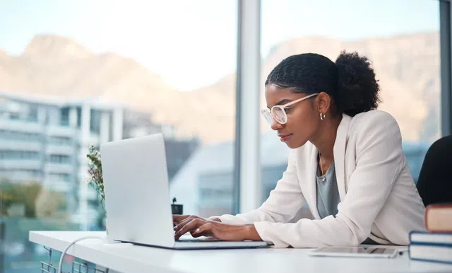 Professional woman working on a laptop in a modern office with a mountain view.