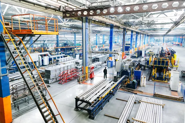 Aerial view of a modern factory interior with machinery and metal products in a spacious layout.
