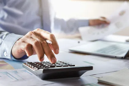 A business professional using a calculator while reviewing financial documents.
