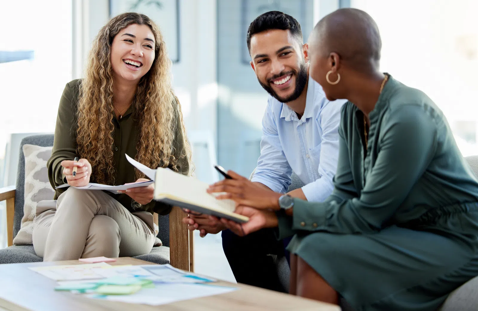 Three diverse professionals collaborate and discuss ideas in a modern office setting.