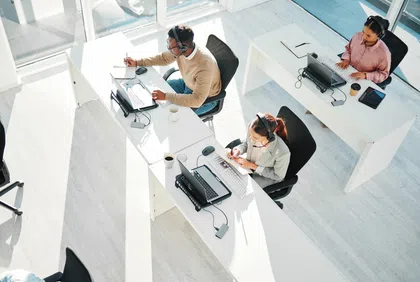Three professionals working at desks in a bright, modern office space.