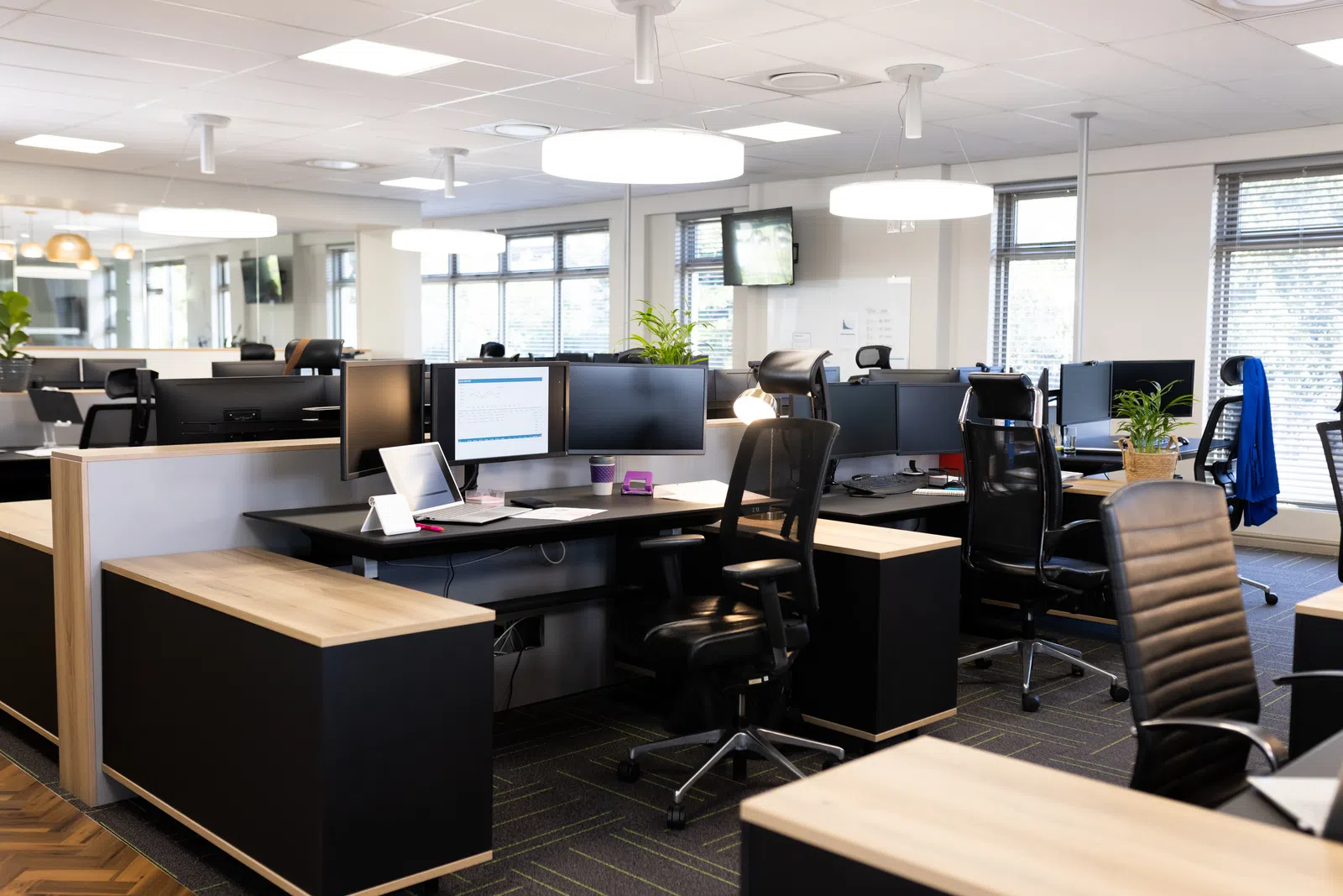 Modern office workspace with sleek desks, ergonomic chairs, and ample natural lighting.