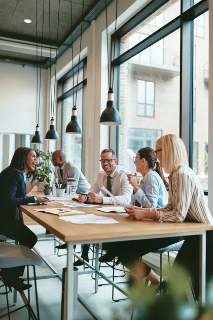 Diverse group of professionals collaborating around a large table in a modern office setting.