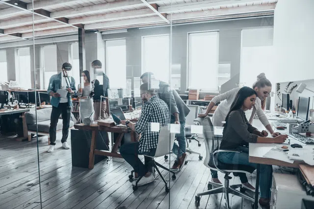 Modern office setting with team collaboration and creative work in progress.