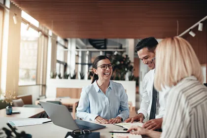 Three professionals in an office discussing ideas and collaborating, showcasing teamwork and positivity.