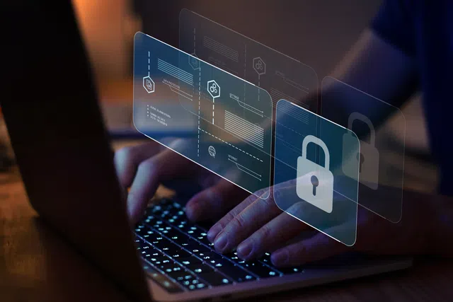 Hands typing on a laptop with digital padlock graphics, symbolizing cybersecurity and data protection.