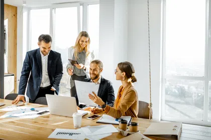 A group of professionals collaborating over a laptop in a bright office space.