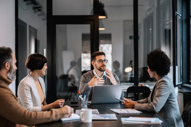 A diverse group of professionals engaged in a collaborative meeting around a conference table.
