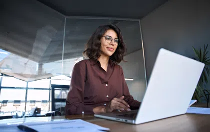 Professional woman working on laptop in modern office environment, focused and engaged in her task.